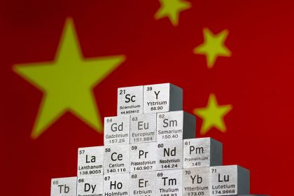 In this photo illustration, metal cubes representing rare earth elements including Scandium (Sc), Yttrium (Y), Neodymium (Nd), Lanthanum (La), and others are stacked in a stepped formation in front of the national flag of China