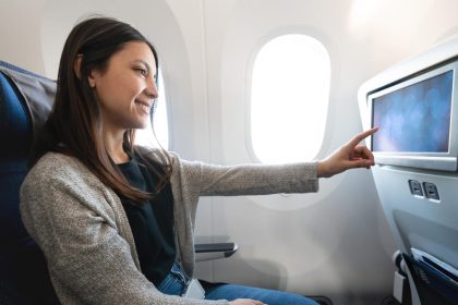 woman traveling by plane and watching onboard entertainment
