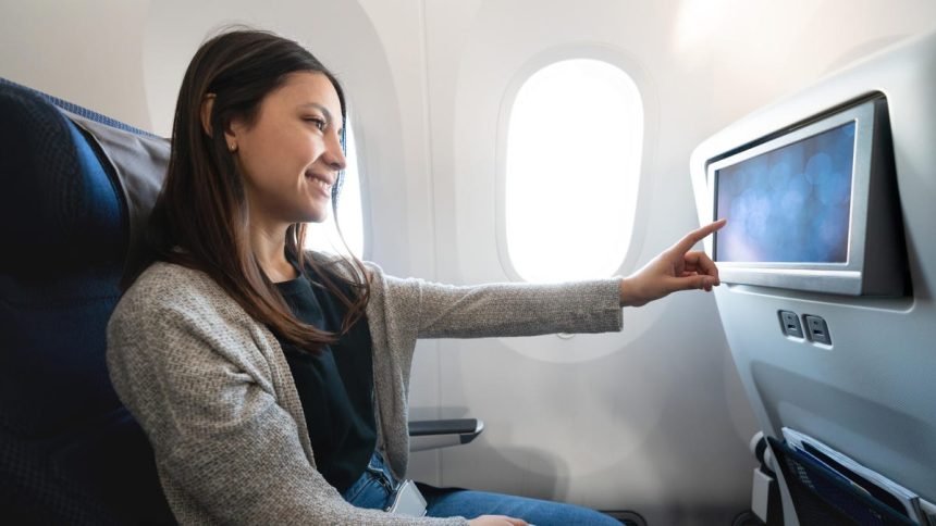 woman traveling by plane and watching onboard entertainment