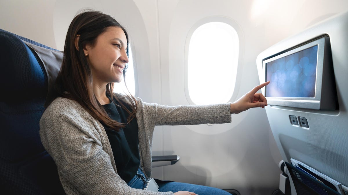 woman traveling by plane and watching onboard entertainment