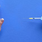 Vaccine refusal concept. Medic hand in glove with syringe. Hand refusing vaccination from measles or Covid-19. Anti-vaccination concept image with refusal gesture.