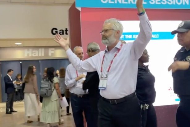Police escort Dr. Steven Kuhn out of a medical conference in New Orleans for handling out copies